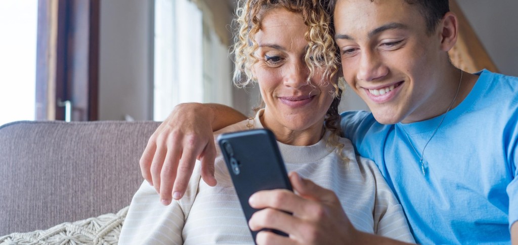 Adolescente con su madre enseñándole el móvil